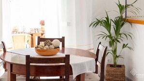 Un comedor con una mesa redonda de madera, sillas, un cuenco de objetos decorativos, bombillas colgantes y una planta en maceta.