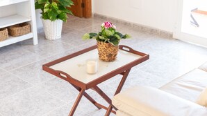 Una pequeña mesa de madera con una vela blanca y una planta en maceta con flores rosas.