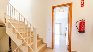 Eine Treppe führt zu einem Raum, in dem ein Feuerlöscher an der Wand angebracht ist.