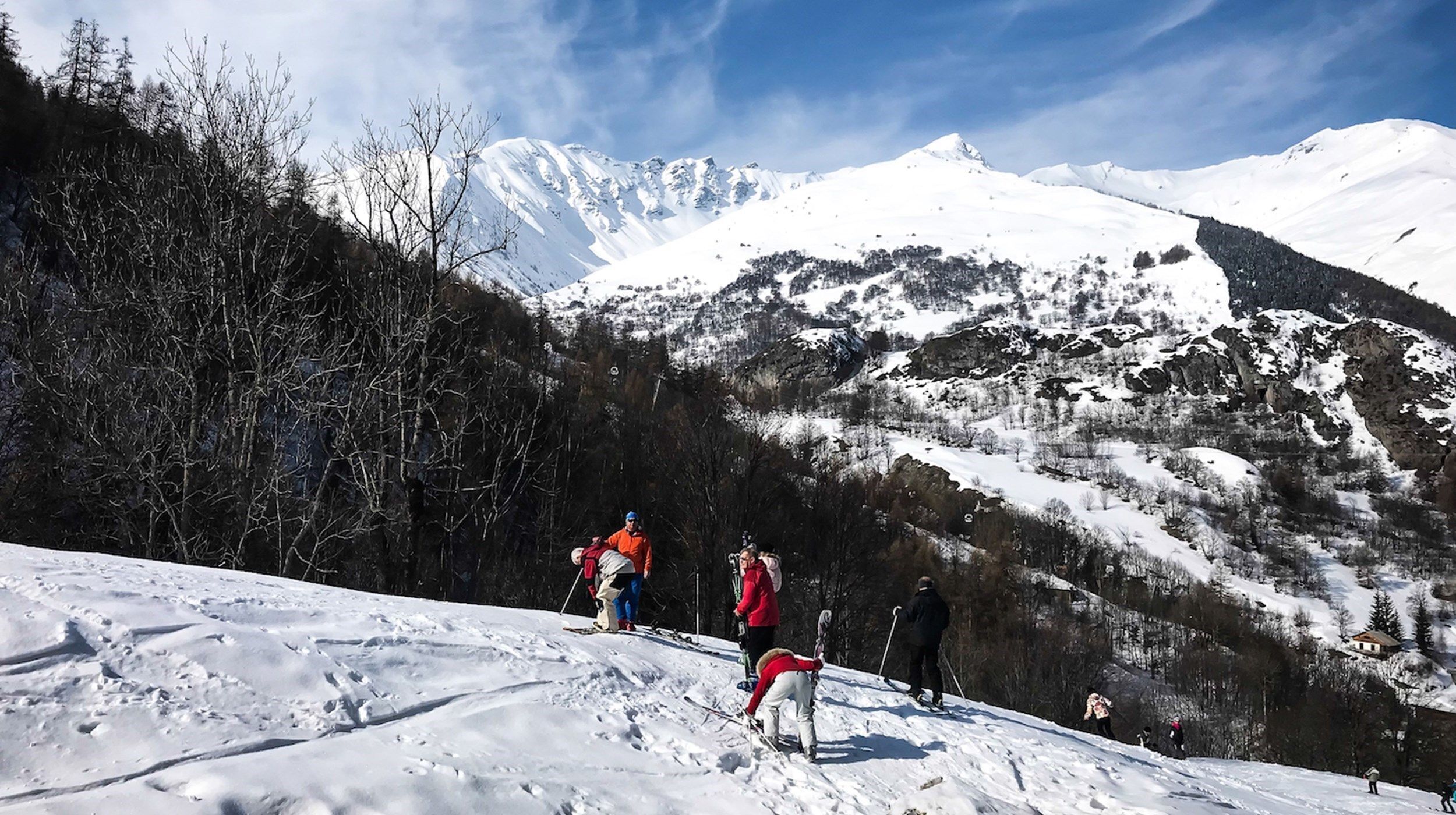 Paesaggio montano innevato con sciatori.