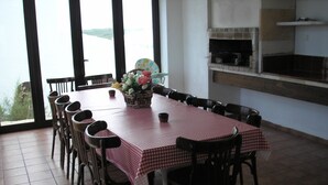 Un comedor con mantel a cuadros rojo y blanco, sillas de madera y un cesto de flores.