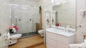 A modern bathroom with a glass shower enclosure, a white sink, and a large mirror.