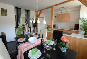 A dining area with a table set for four, a kitchen in the background, and a mirror reflecting the room. - Enjoy holiday with ambiance (Königstein)
