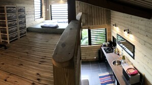 Ein gemütliches Blockhaus mit Schlafzimmer im oberen Bereich, einer Küchenzeile und einem kleinen Badezimmer.