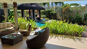 Un espace patio aménagé avec des meubles en osier, une piscine et une végétation luxuriante.