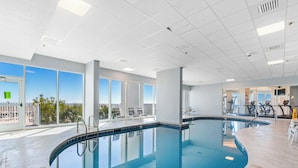 Une piscine intérieure offrant une vue dégagée sur le paysage urbain grâce à de grandes fenêtres.