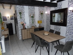 A dining area with a wooden table, grey chairs, a small cabinet, and a mirror on the wall.