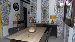 Un comedor con una mesa y sillas de madera, una cocina al fondo y papel tapiz estampado.