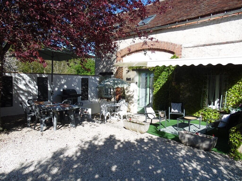 Eine Terrasse mit Grill, Sitzgelegenheit und überdachtem Bereich.