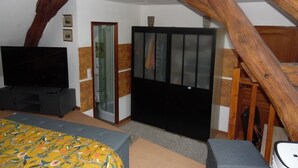 Un dormitorio con cama, televisión, armario y viga de madera en el techo.