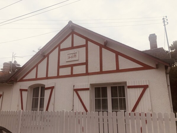 Ein Gebäude mit weißer Fassade und roten Akzenten, mit einem Schild mit verspielten Schriftzügen.