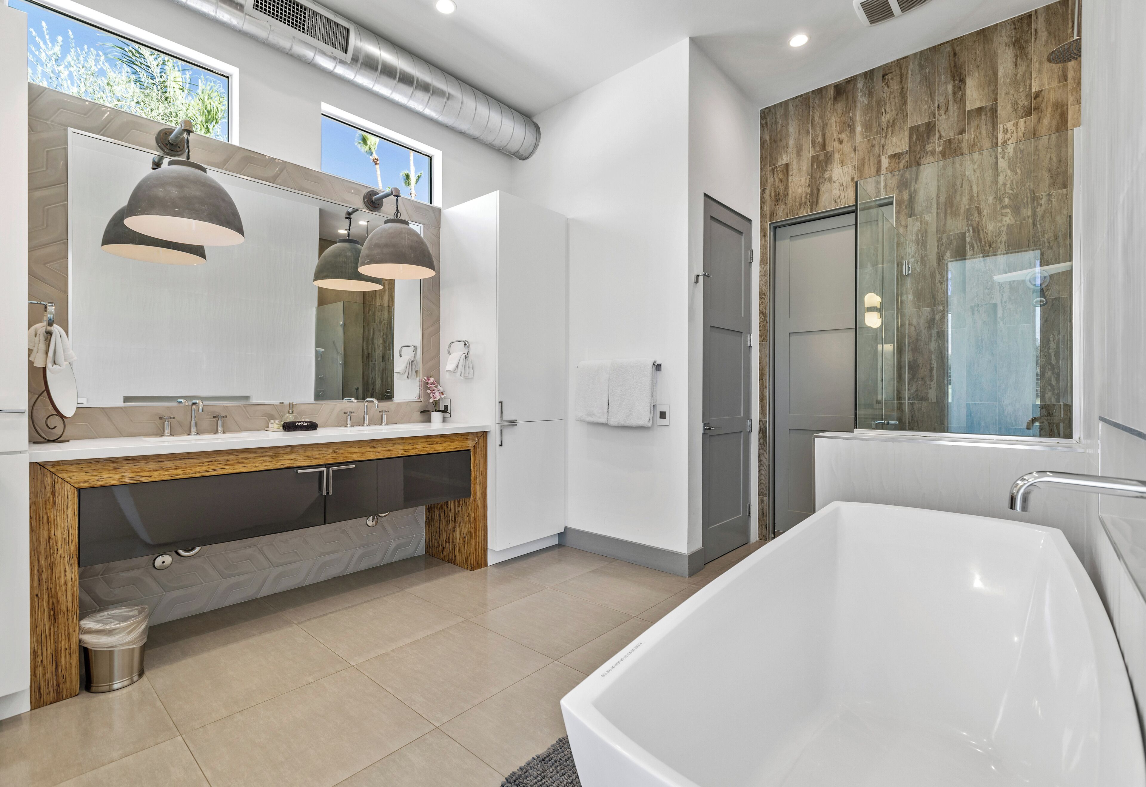 Un baño moderno con una bañera grande, un tocador con espejo y una zona de ducha.