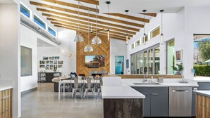 Una cucina moderna con isola centrale, illuminazione a sospensione e parete con decorazione a spina di pesce.