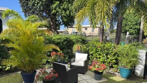 Een terras met buitenmeubilair, planten in potten en een pad van stenen.