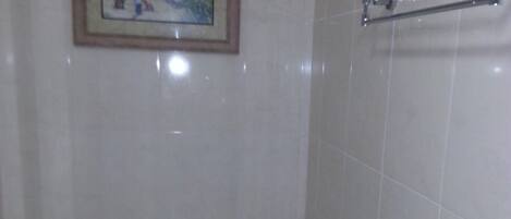 A bathroom with a toilet, a trash can, and a framed picture on the wall.