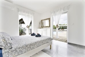 A bedroom with a bed, a mirror, and a view of the outside balcony. - Exceptional villa with sea view, infinity pool -Sainte Anne-12 people (Sainte Anne)