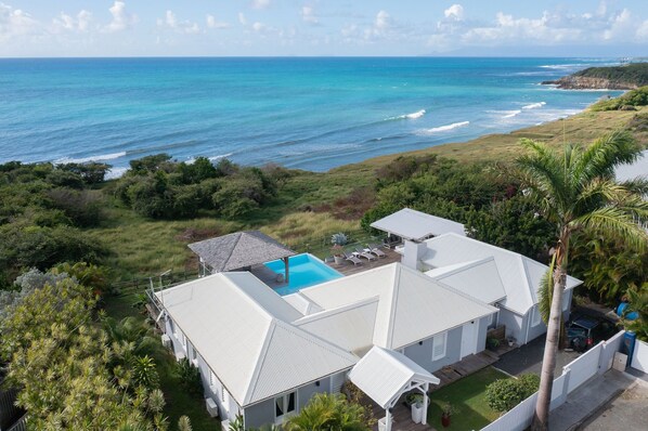 A house with a swimming pool, surrounded by lush greenery and overlooking the ocean. - Exceptional villa with sea view, infinity pool -Sainte Anne-12 people (Sainte Anne)