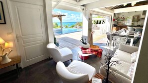 A modern interior with a view of the ocean, a dining area, and a kitchen. - Exceptional villa with sea view, infinity pool -Sainte Anne-12 people (Sainte Anne)