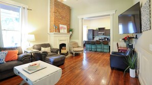 A living room with a fireplace, leather sofas, a coffee table, and a TV mounted on the wall. - 4 Bedrooms 2 Bath All New Historical Home In The Heart Of Springfield, MO (Springfield)