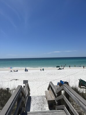 A wooden boardwalk leading to a beach with clear skies.