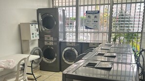Eine Wäscherei mit gestapelten Waschmaschinen, einer Trockenstation und einer Bedienkonsole.