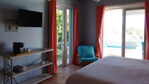 Un dormitorio con una cama, una silla, cafetera y televisor en la pared.