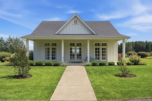 Une maison à deux étages avec un porche à l’avant, une allée et une pelouse bien entretenue.