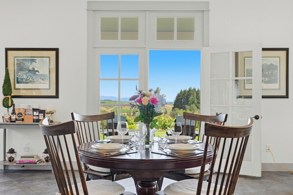 A dining table set for four with chairs, a vase of flowers, and framed artwork on the walls.