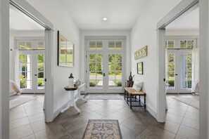 A hallway with a bench, a table with a lantern, and a door leading outside.