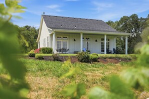 A single-story house with a porch, a dining area with outdoor furniture, and a well-maintained garden. - Southfield Cottage: A Perfect Wine Country Stay! (Newberg)