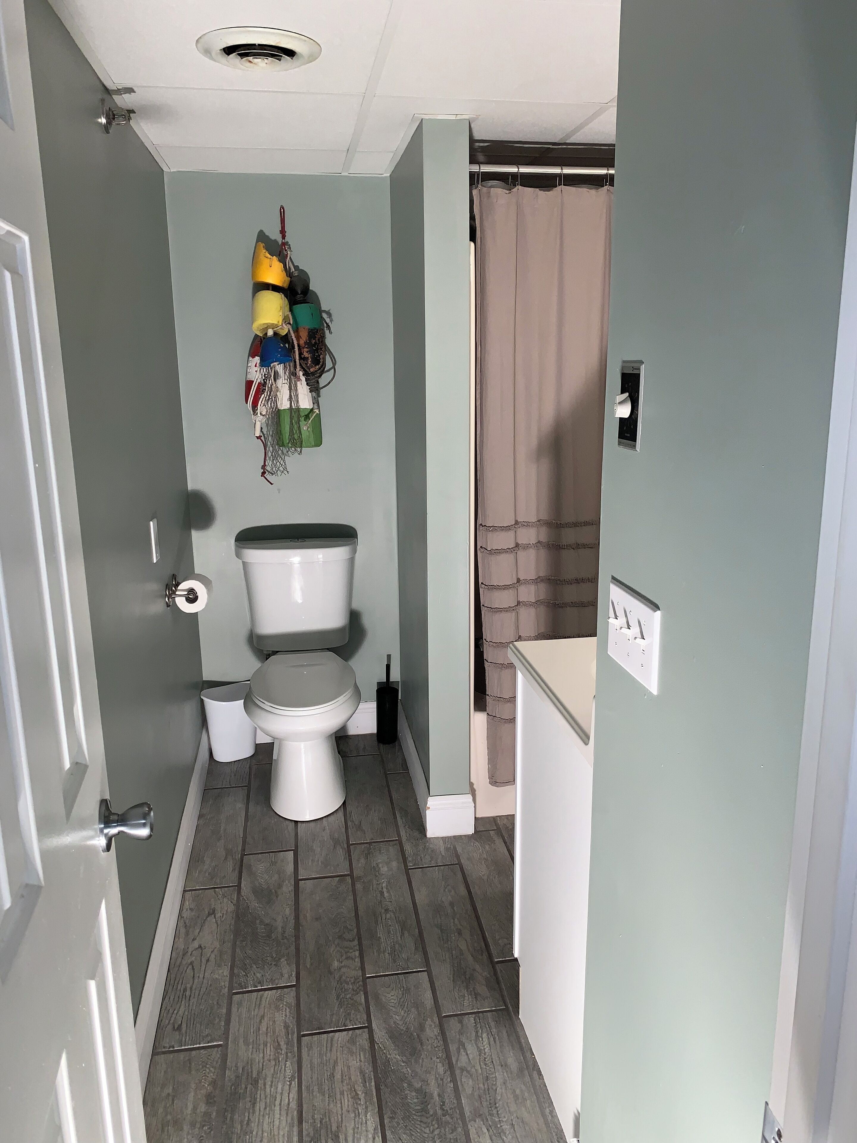 Une petite salle de bain avec des toilettes, une poubelle et un rideau de douche.