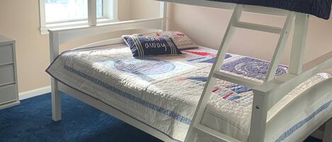 A bunk bed with a ladder, a window with blinds, and a wall sign that reads "SWIM FRESH FISH".
