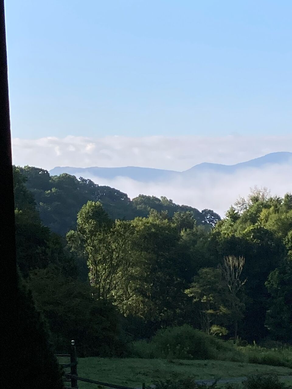 Een uitzicht op een bergachtig landschap met bomen en een heldere lucht.