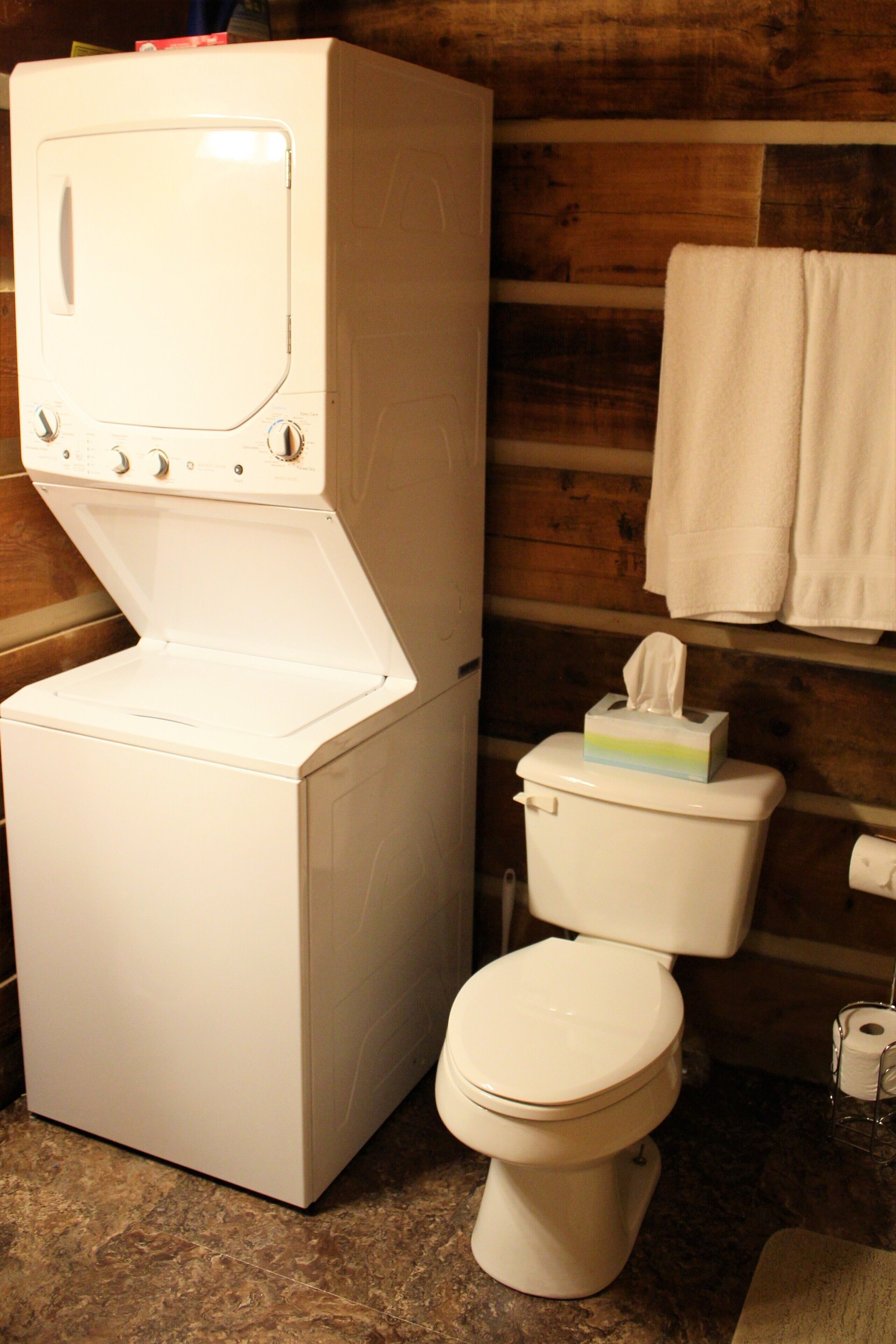 A compact bathroom with a white washing machine, a toilet, and a towel rack.