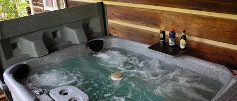 Un jacuzzi con pared exterior de madera, un asiento integrado y un estante con botellas.