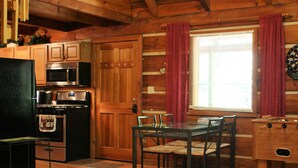 L’intérieur d’un chalet en bois comprend une cuisine, un coin repas et un jeu de fléchettes.