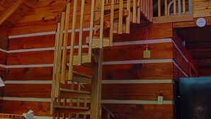 L’intérieur d’une cabane en bois est agrémenté d’un escalier en colimaçon menant à une mezzanine.