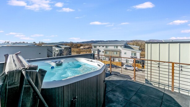 Un jacuzzi sur un balcon, avec vue sur des immeubles et un plan d’eau en arrière-plan.
