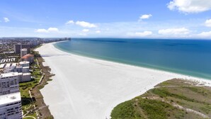 Un paisaje urbano costero con una amplia playa de arena, edificios altos y un cielo azul despejado.