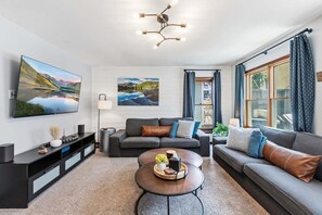 Ein modernes Wohnzimmer mit Flachbildfernseher, einer Couch, einem Couchtisch und Kunstwerken an den Wänden.