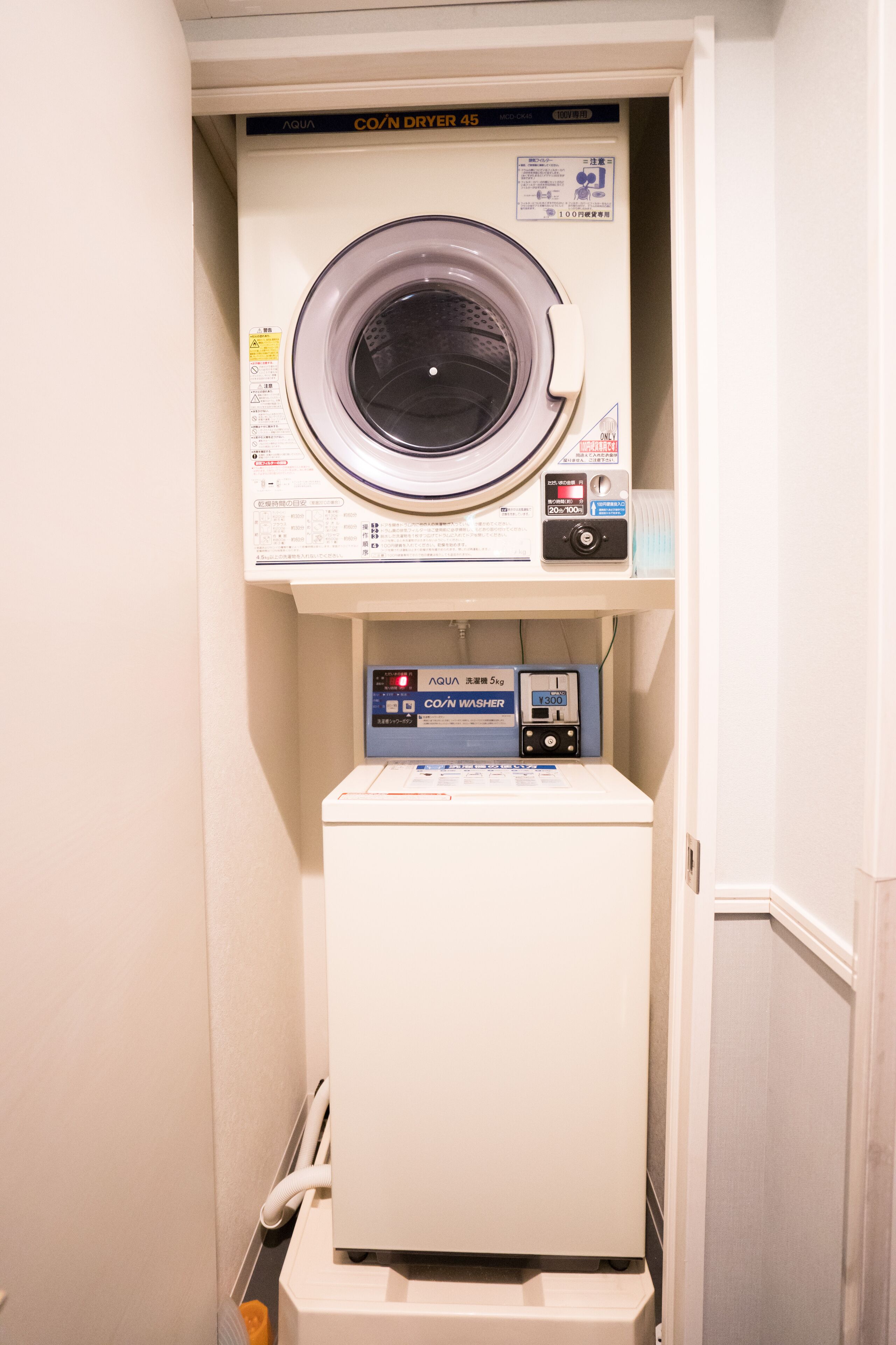 A compact laundry room with a front-loading washing machine and a stacked dryer.