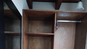 A wooden wardrobe with multiple shelves and a hanging rod. - Hotel Mansion del Rey (Antigua Guatemala)