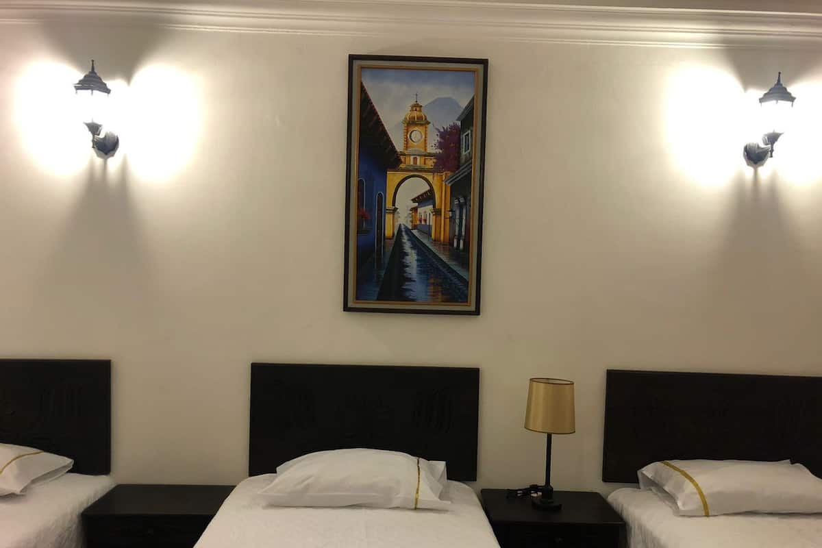 Una habitación de hotel con dos camas, un cuadro de una torre y apliques de pared.