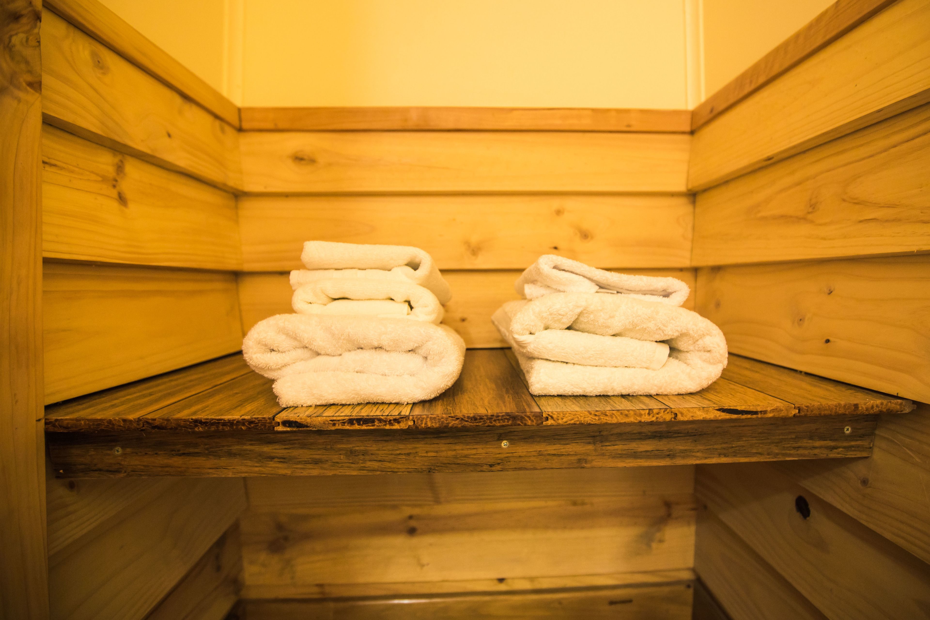 A wooden sauna with two towels stacked on a shelf.