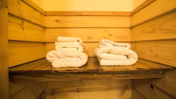 Una sauna de madera con dos toallas apiladas en un estante.