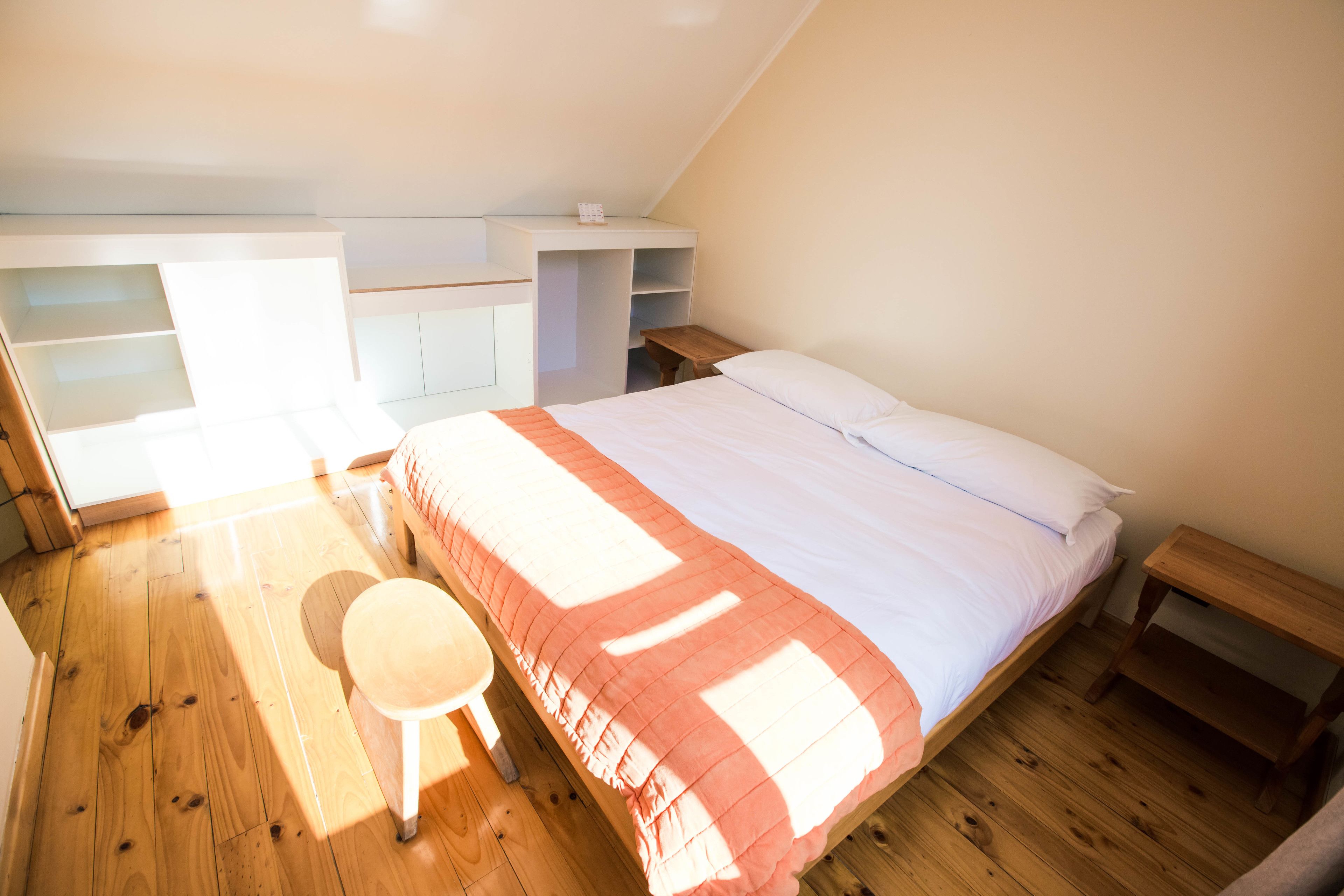 Une chambre à coucher avec un lit, un plancher en bois, un bureau et une chaise.