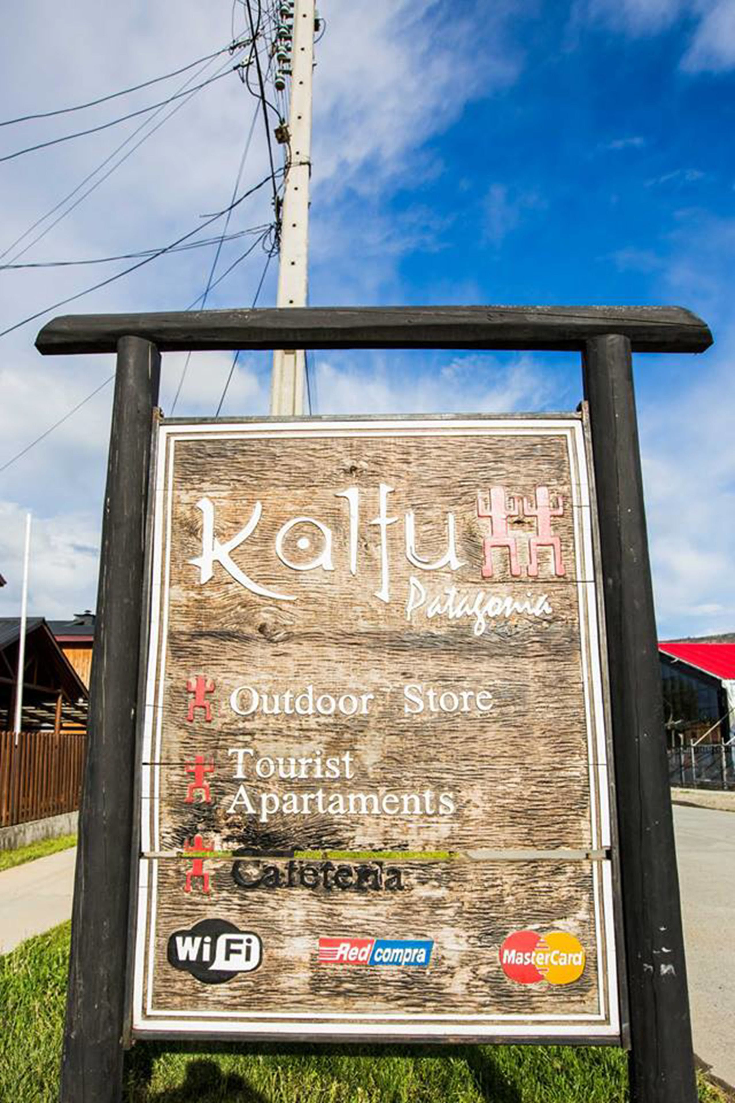 A wooden signboard for Kalu Patuxent, listing amenities like an outdoor store, tourist apartments, and cafeteria.