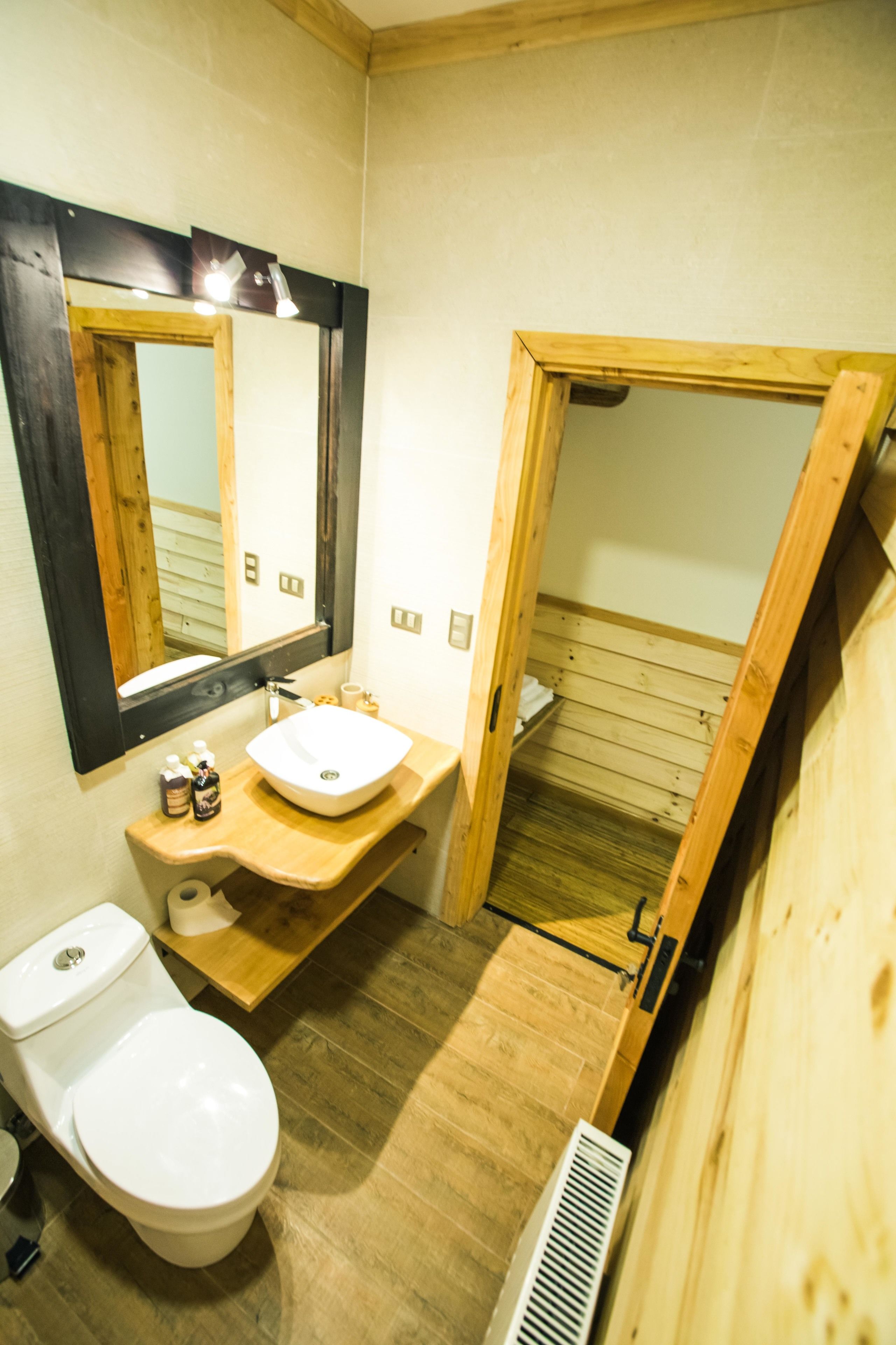 Un baño de madera con un lavabo blanco, un espejo y un inodoro.