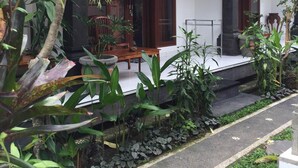 A traditional house with a tiled roof, a wooden porch, and various potted plants. - Pondok Ayu Homestay (Ubud)