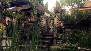 A traditional temple complex with stone structures, steps leading to a central shrine, and lush tropical vegetation. - Pondok Ayu Homestay (Ubud)